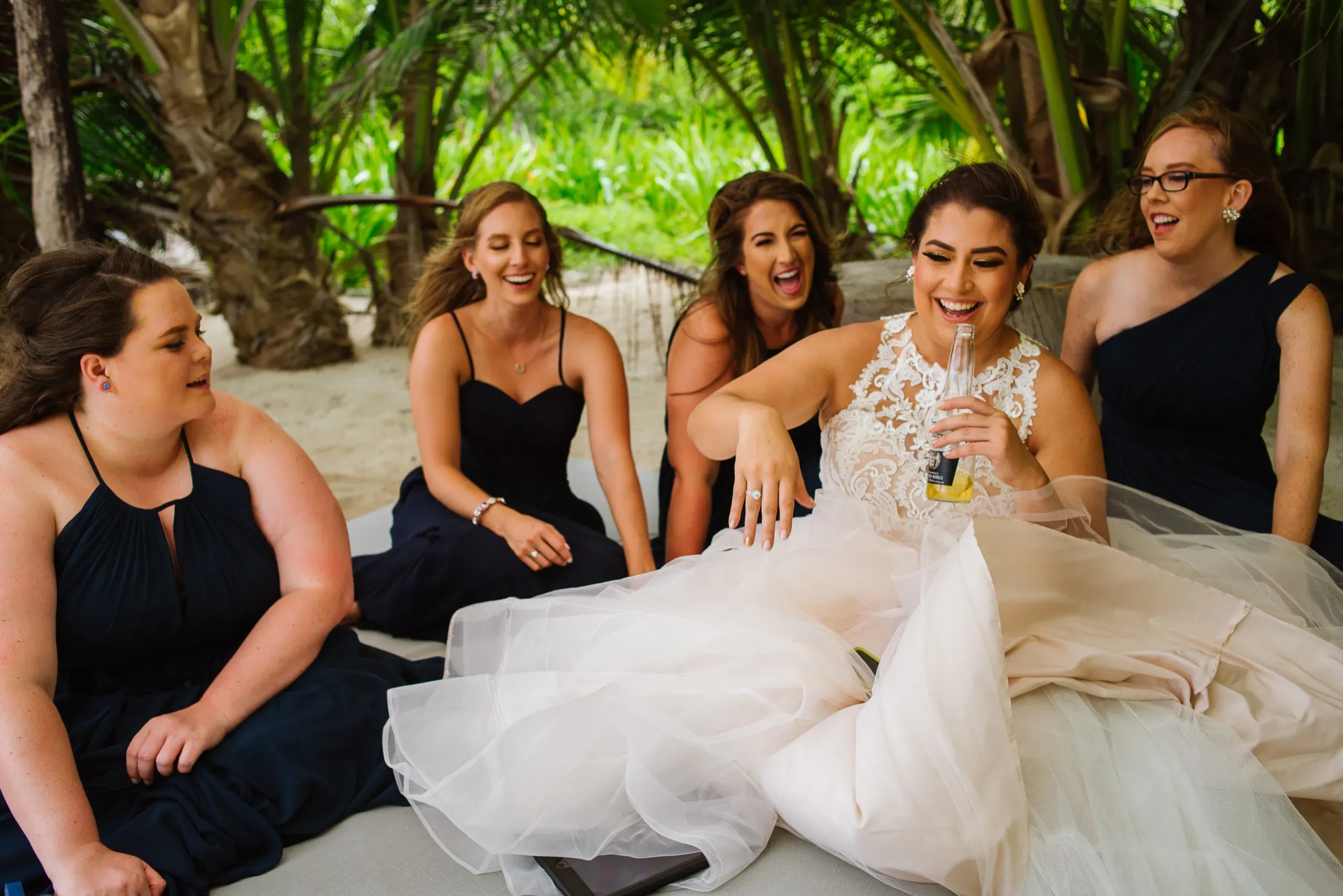 Bride and bridesmaids laughing together at tropical Cancun beach wedding celebration in Riviera Maya Mexico