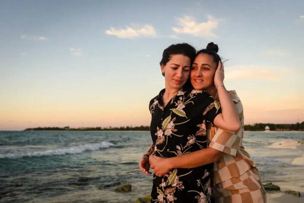 Two women embracing after surprise proposal on Playa del Carmen beach, engagement photography by Tam Rico Photo