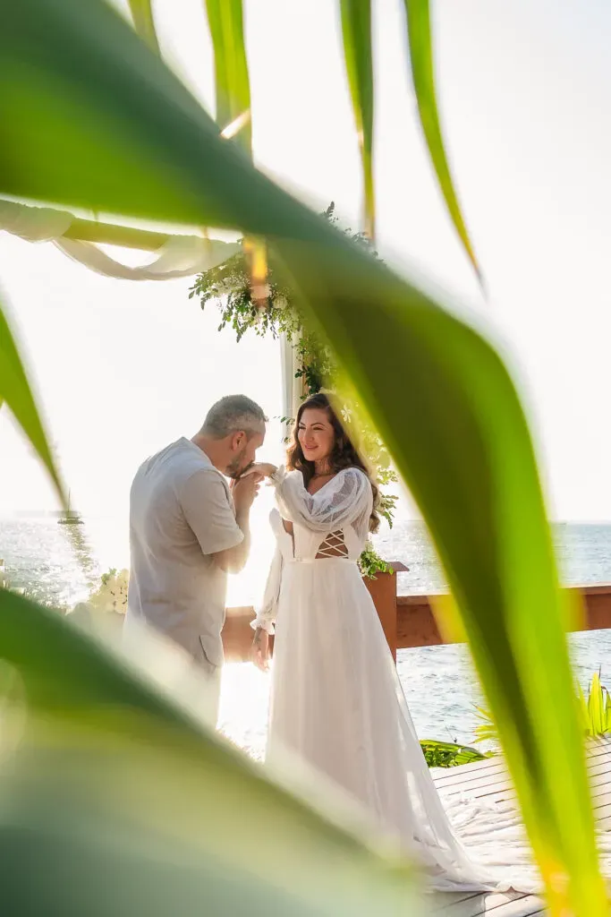 Romantic beach wedding ceremony in Cancun with couple exchanging vows on wooden deck overlooking Caribbean Sea, Mexico