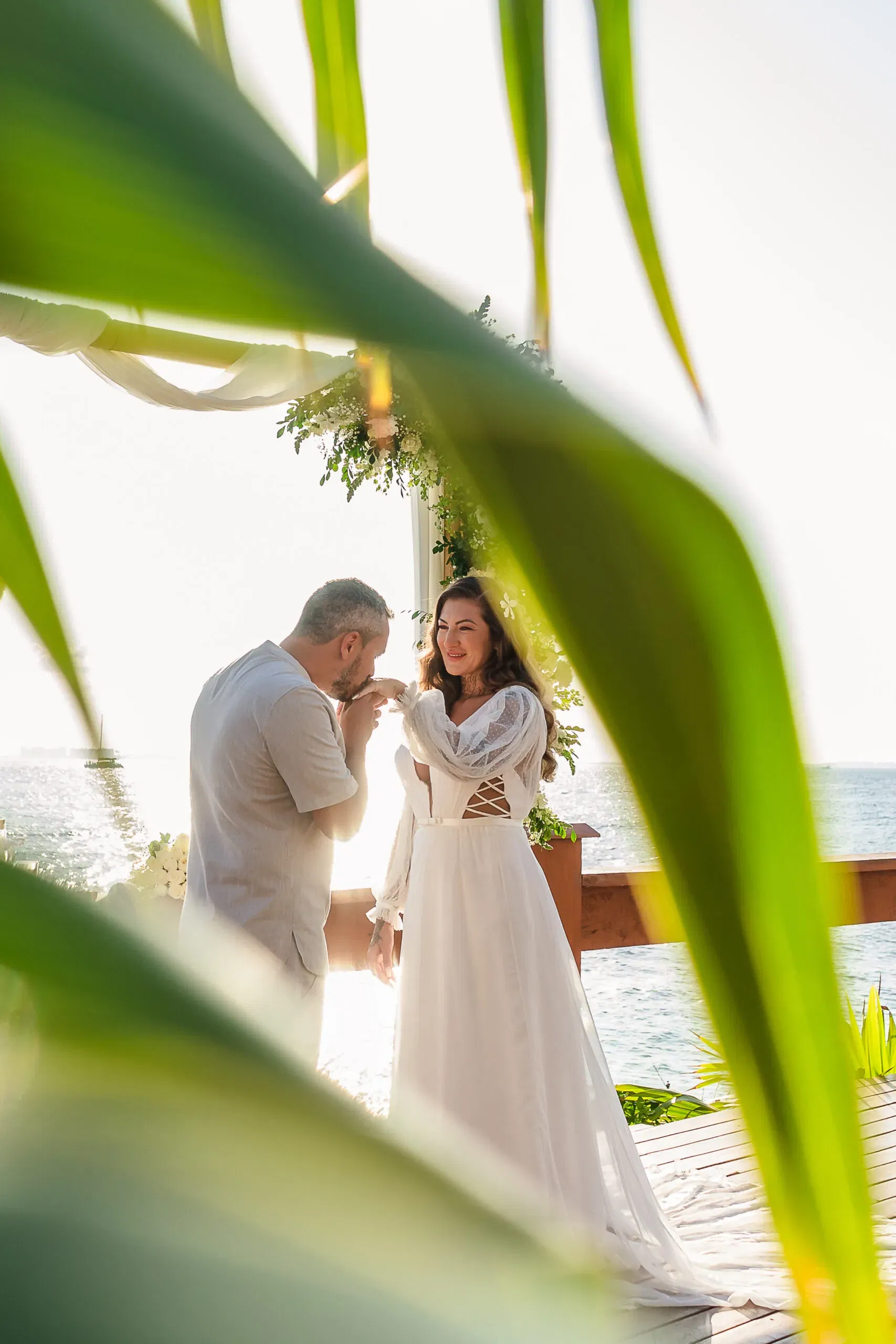 Romantic beach wedding ceremony in Cancun with couple exchanging vows on wooden deck overlooking Caribbean Sea, Mexico