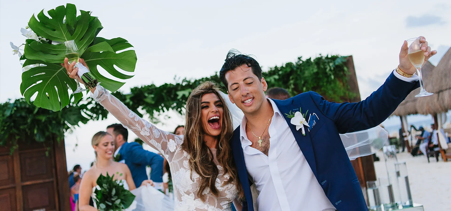 Newlywed couple celebrating with tropical bouquet at beachfront wedding ceremony in Cancun Riviera Maya Mexico