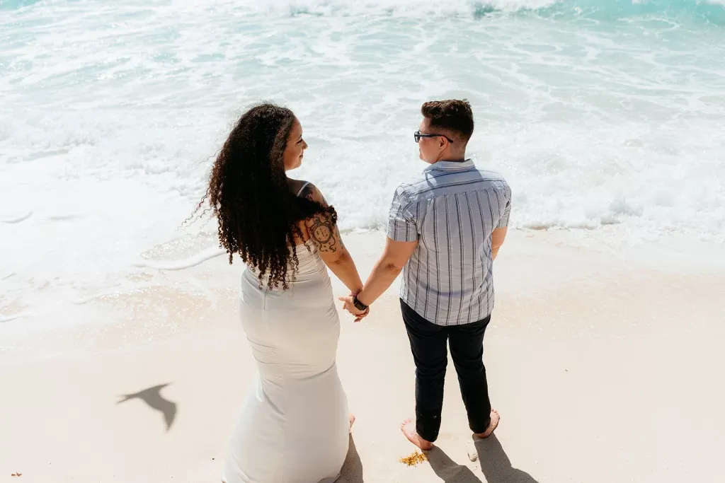 Romantic couple holding hands on pristine Cancun beach - destination wedding photography in Riviera Maya Mexico