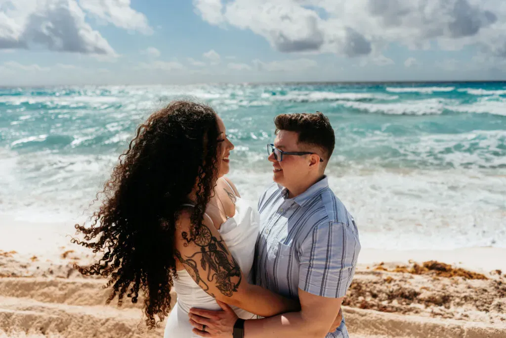 Romantic couple embracing on Cancun beach during engagement photo session with turquoise Caribbean Sea and white sand