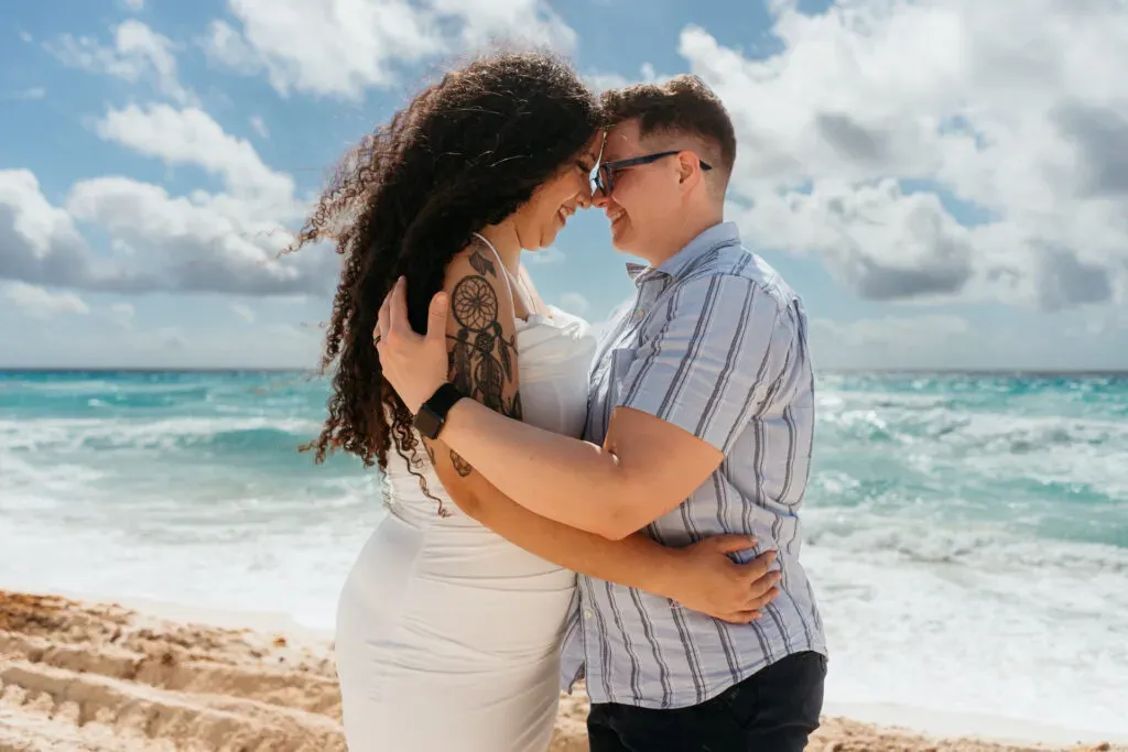 Romantic couple embracing on pristine Cancun beach during engagement photo session in Riviera Maya Mexico