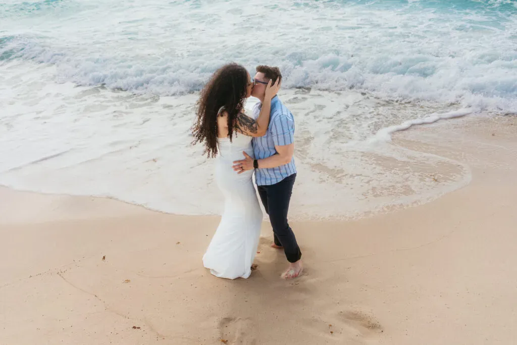 Romantic beach wedding couple kissing on pristine Riviera Maya shore with turquoise waves in Cancun Mexico destination wedding