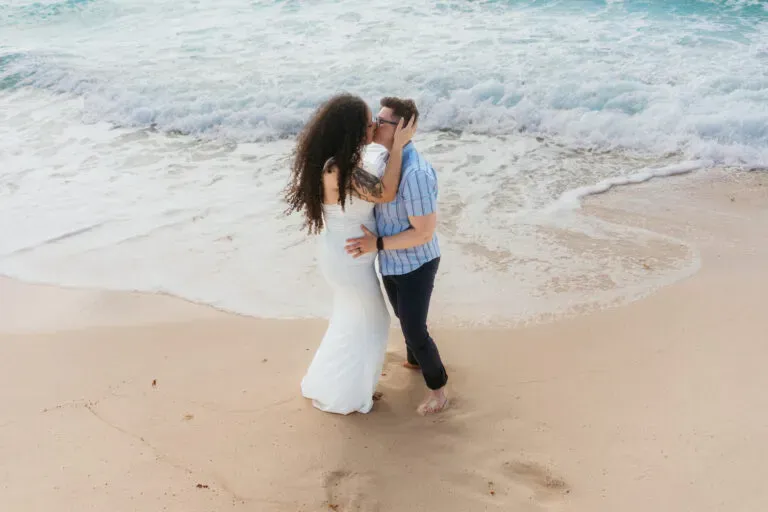 Romantic beach wedding couple kissing on pristine Riviera Maya shore with turquoise waves in Cancun Mexico destination wedding
