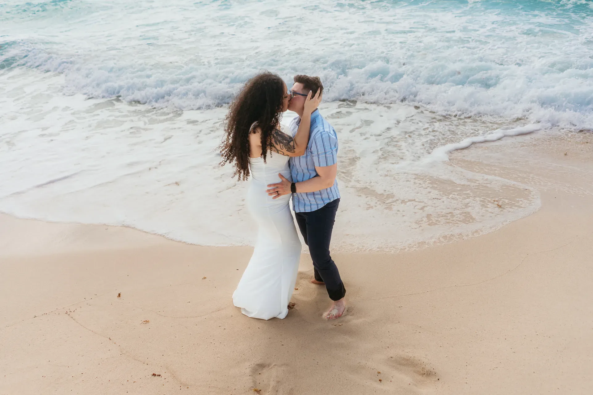 Romantic beach wedding couple kissing on pristine Riviera Maya shore with turquoise waves in Cancun Mexico destination wedding