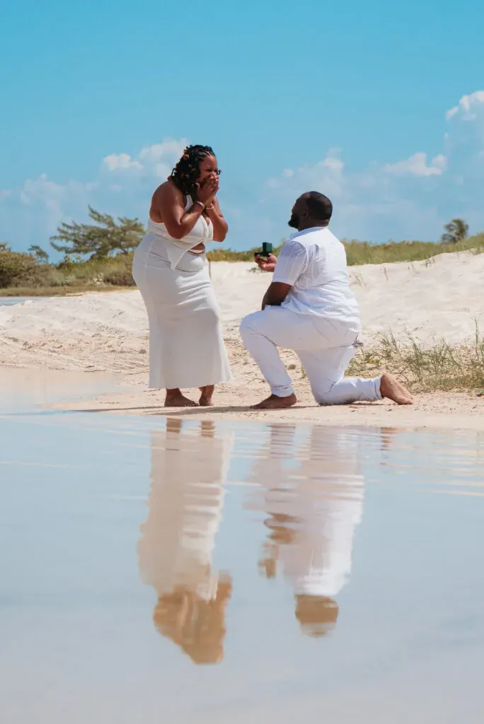 Beach proposal in Cancun Mexico with couple in white outfits reflected in wet sand at tropical destination wedding location