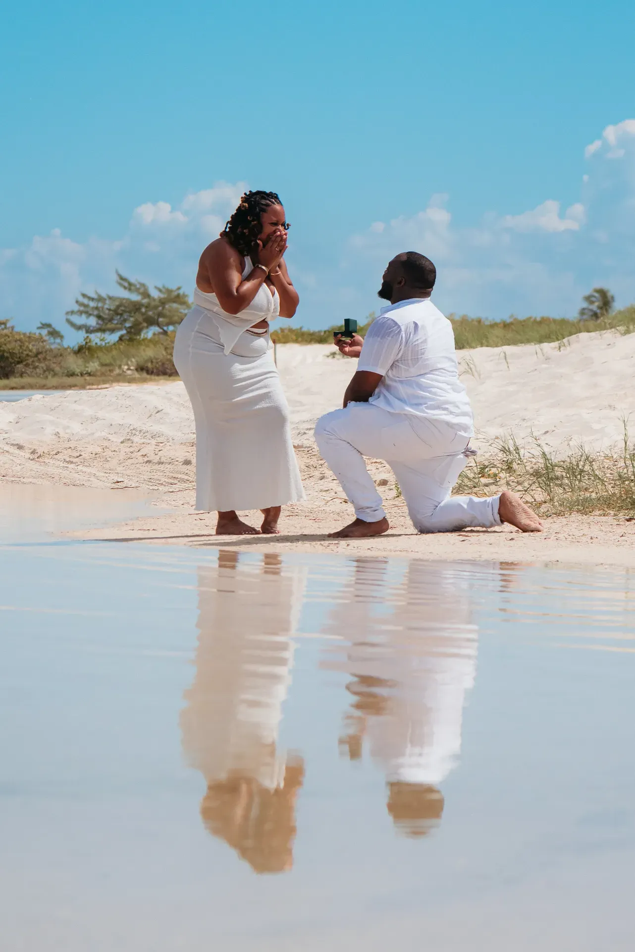 Charly kneeling to propose to Asia on the beach in Isla Blanca, Cancun, surprise engagement photographer