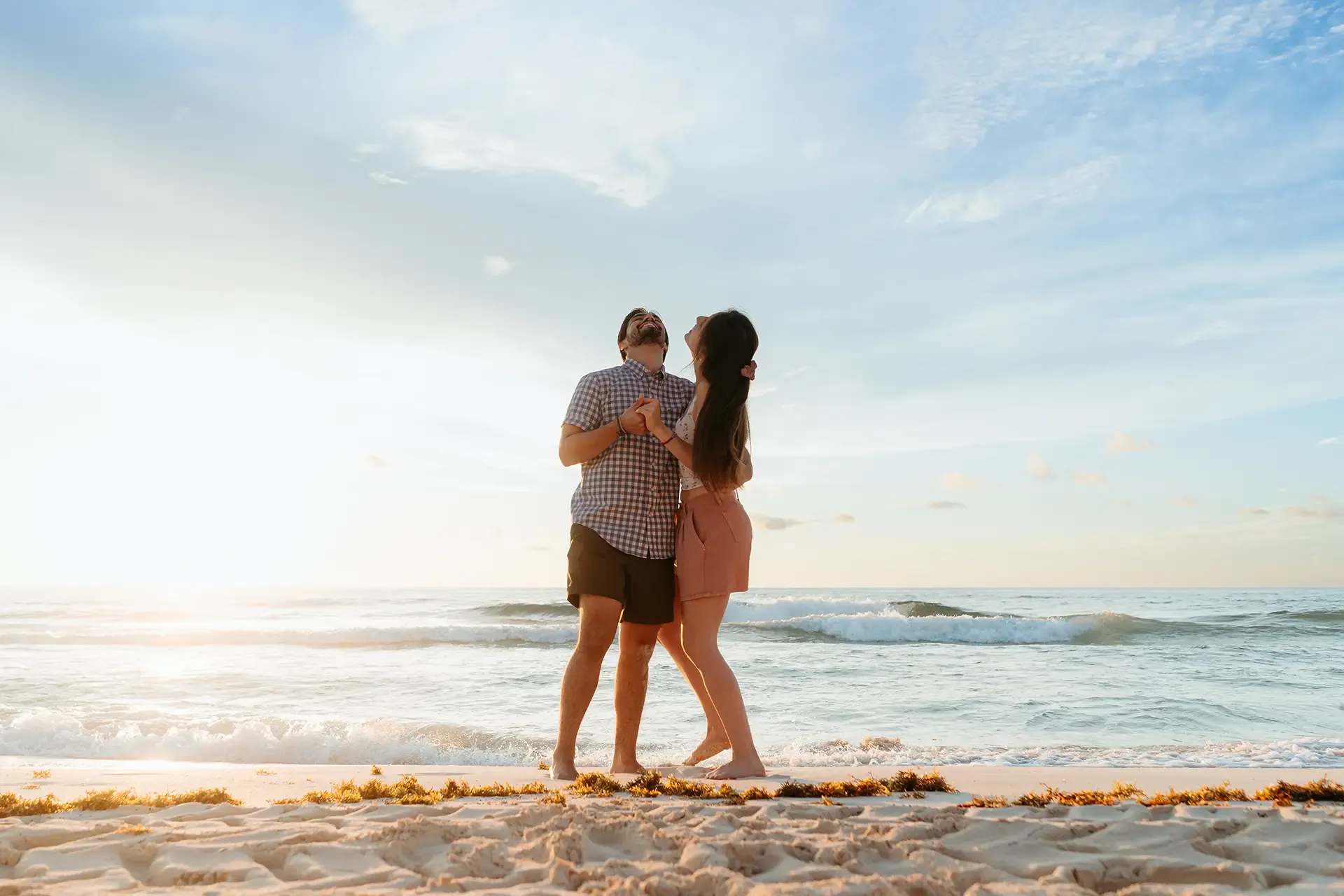 Romantic couple embracing on Cancun beach at sunset - destination wedding photography Riviera Maya Mexico