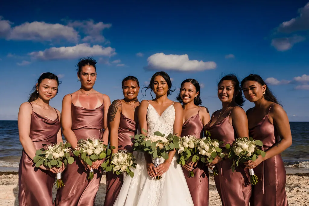Beach wedding bridesmaids in rose gold dresses holding bouquets in Cancun Mexico destination wedding photography
