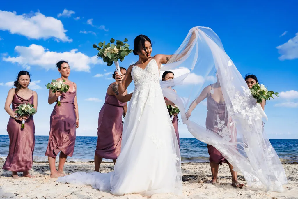 Bride with bridesmaids in dusty rose dresses on Cancun beach - destination wedding photography Riviera Maya Mexico