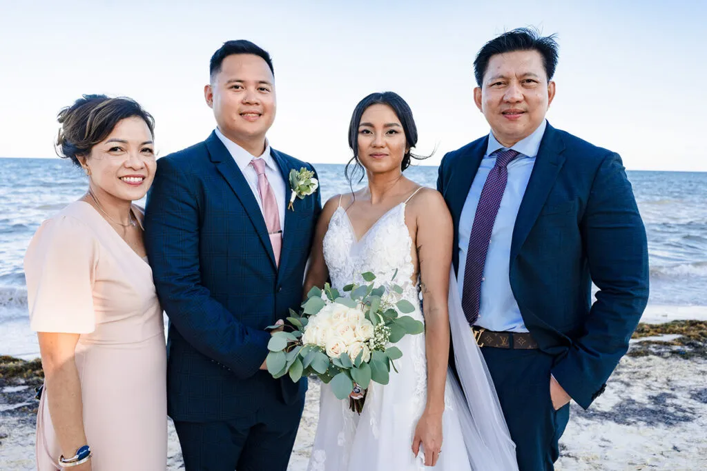 Beach wedding photography Cancun family portrait with bride groom parents ocean backdrop Riviera Maya Mexico destination wedding