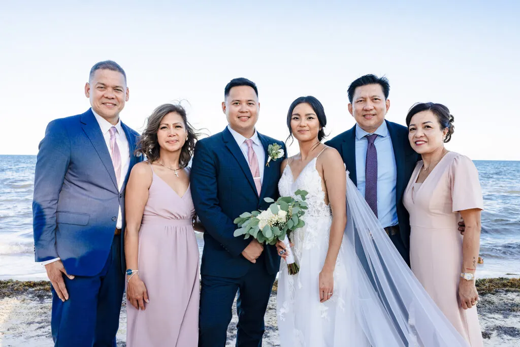 Beach wedding family portrait in Cancun - bride and groom with parents celebrating destination wedding in Riviera Maya