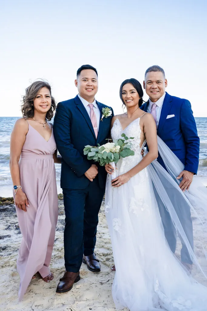 Beach wedding family portrait with bride, groom and parents in Cancun Riviera Maya Mexico destination wedding photography