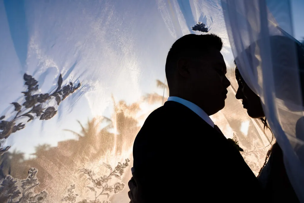 Romantic wedding silhouette of bride and groom with flowing veil at sunset in Cancun Riviera Maya Mexico destination wedding