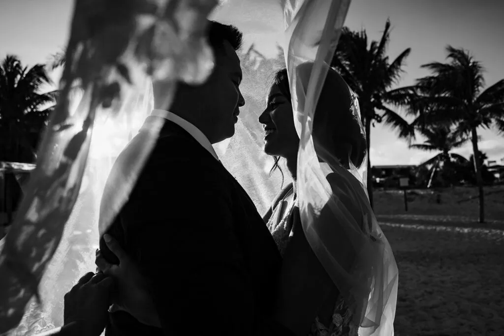 Romantic black and white wedding portrait of bride and groom with flowing veil in tropical Cancun Riviera Maya Mexico