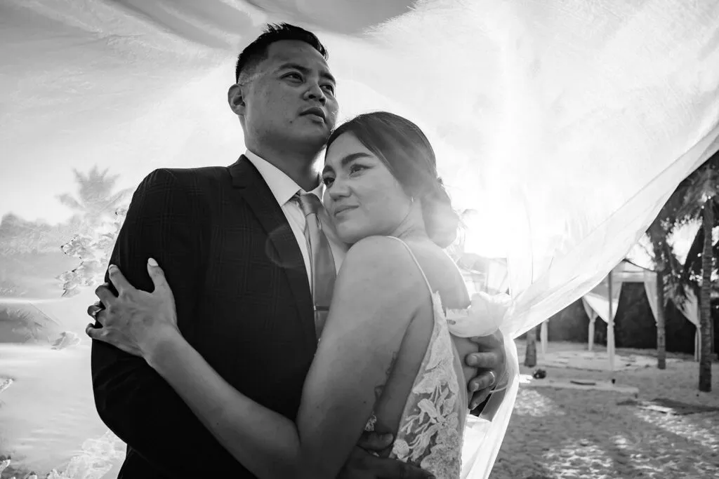 Romantic black and white wedding portrait of bride and groom embracing on Cancun beach in Riviera Maya Mexico