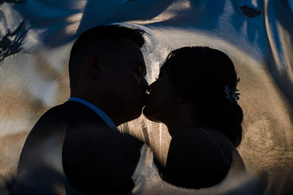 Romantic couple silhouette kissing in Cancun cenote cave during destination wedding photography session in Riviera Maya