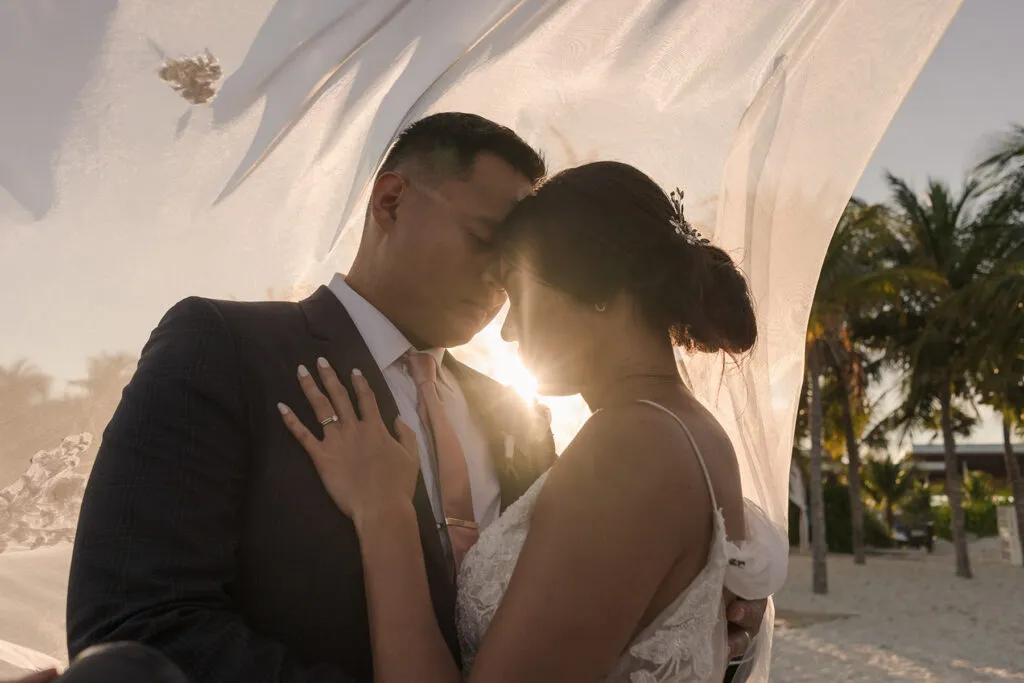 Romantic wedding couple embracing at sunset in Cancun Mexico with palm trees and tropical beach destination backdrop
