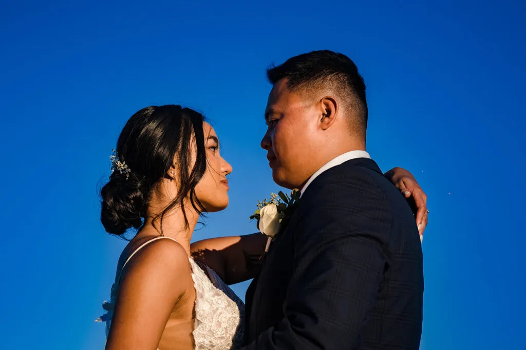 Romantic wedding couple embracing at sunset in Cancun Mexico with vibrant blue sky backdrop for destination wedding photos