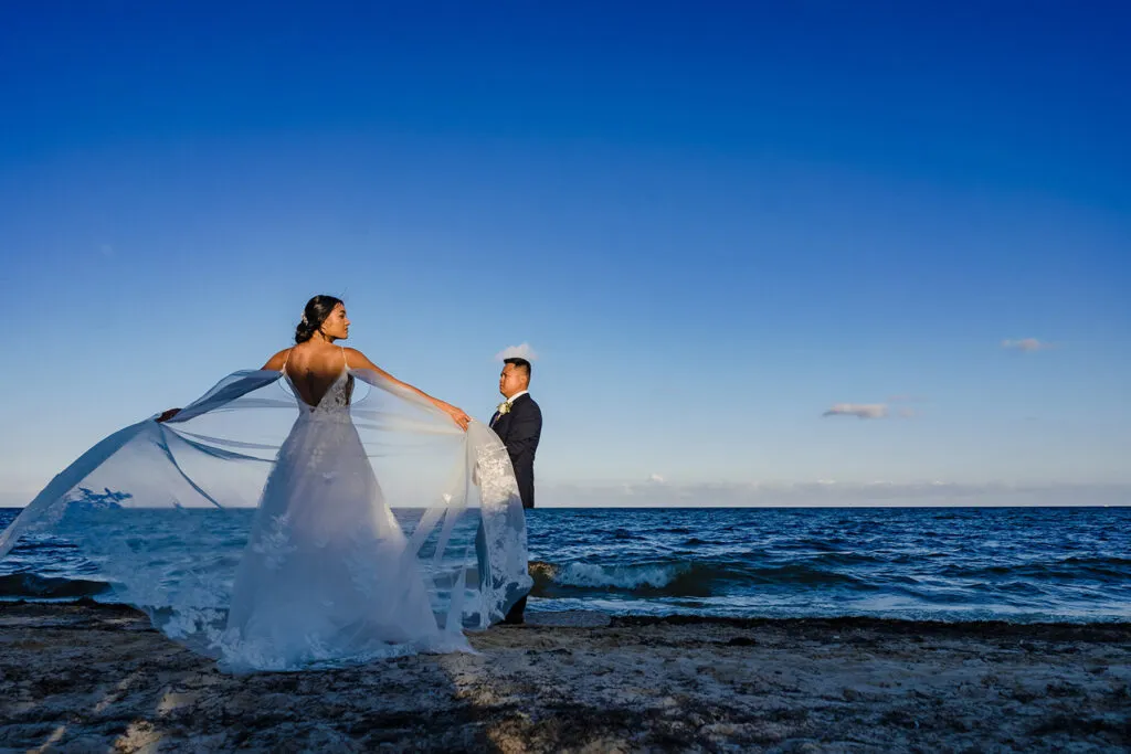 Bride and groom beach wedding photography session at sunset in Cancun Riviera Maya Mexico with flowing veil