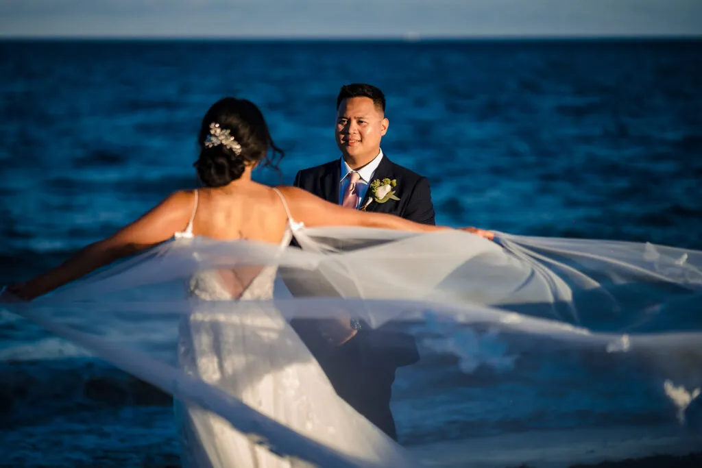 Bride and groom beach wedding portrait with flowing veil at sunset in Cancun Riviera Maya Mexico destination wedding