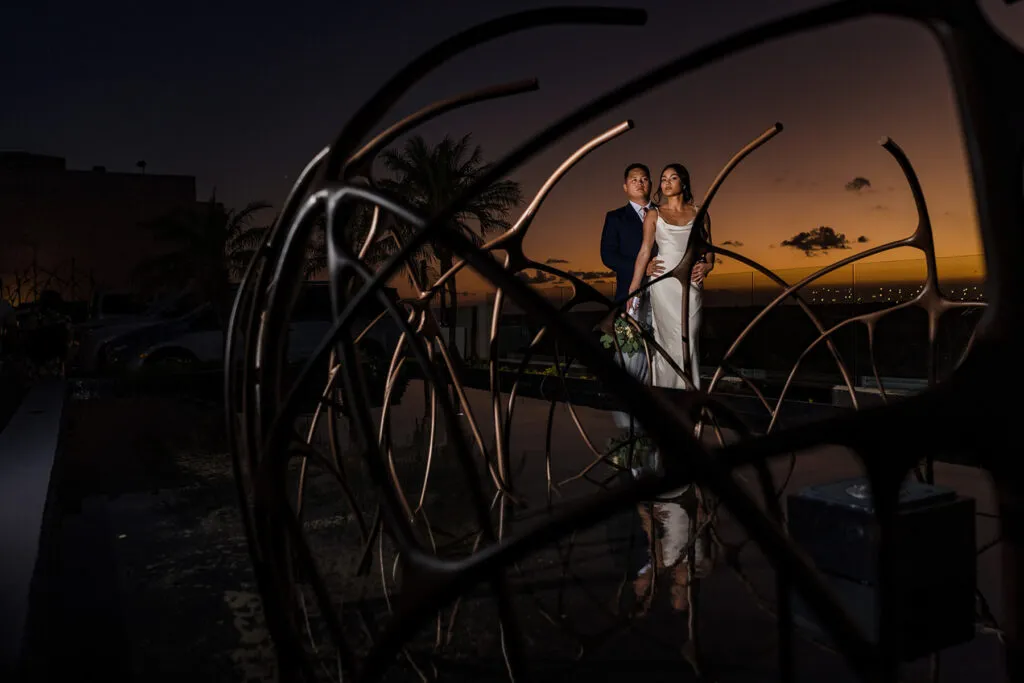 Romantic couple portrait at sunset in Cancun with modern sculpture, luxury wedding photography in Riviera Maya Mexico