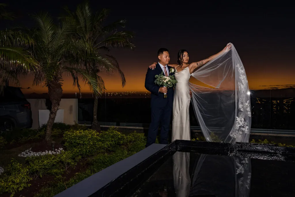 Romantic sunset wedding portrait of bride and groom by pool with palm trees in Cancun Riviera Maya Mexico destination wedding