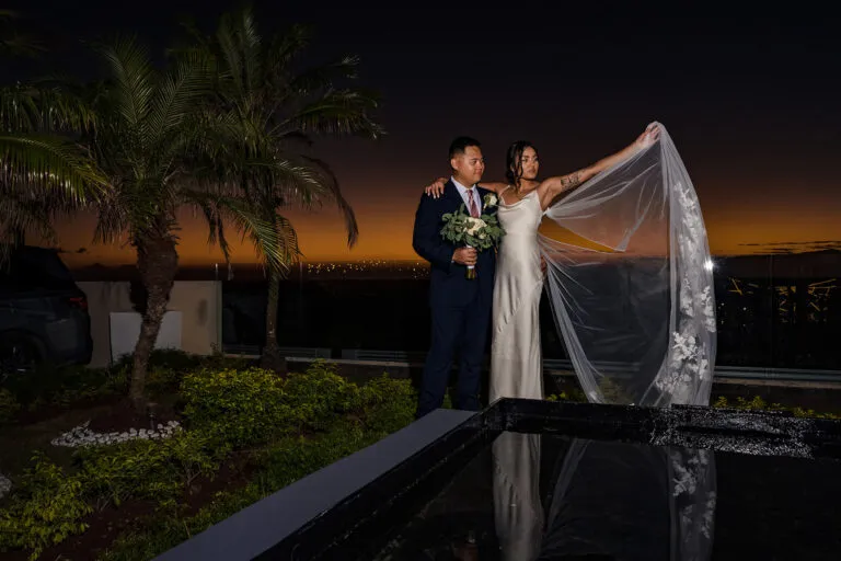 Romantic sunset wedding portrait of bride and groom by pool with palm trees in Cancun Riviera Maya Mexico destination wedding