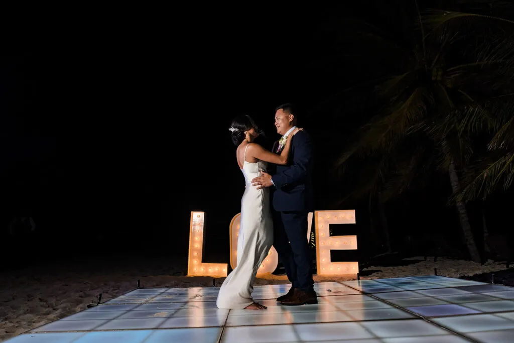 Bride and groom first dance on beach with LOVE marquee lights at Riviera Maya destination wedding in Cancun Mexico