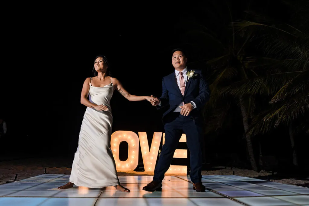 Bride and groom dancing on illuminated dance floor with LOVE marquee letters at Cancun Riviera Maya wedding reception