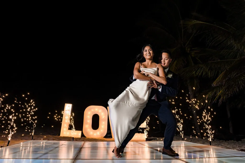 Romantic couple dancing at night wedding celebration with sparklers and LOVE sign in Cancun Riviera Maya Mexico