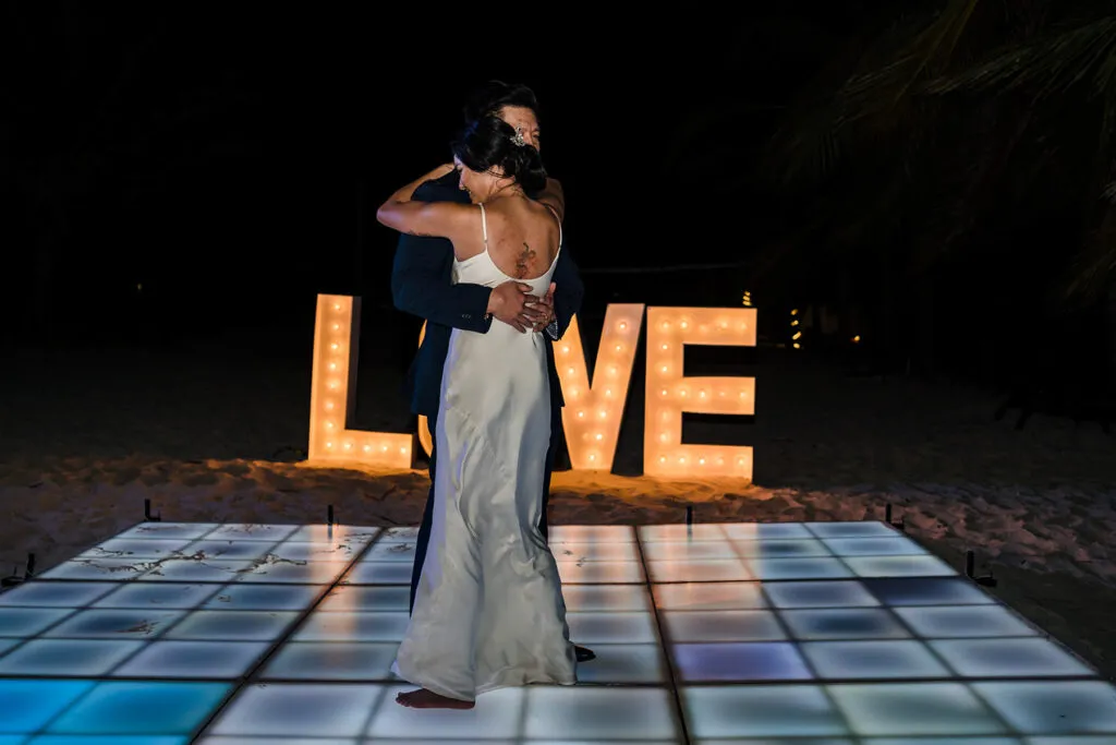 Romantic first dance on illuminated floor with LOVE sign at luxury Riviera Maya beach wedding in Cancun Mexico