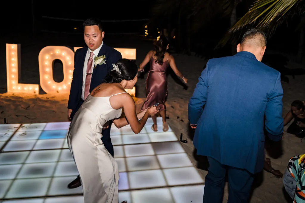 Wedding reception dancing on LED dance floor with LOVE sign at tropical Cancun Riviera Maya destination wedding celebration