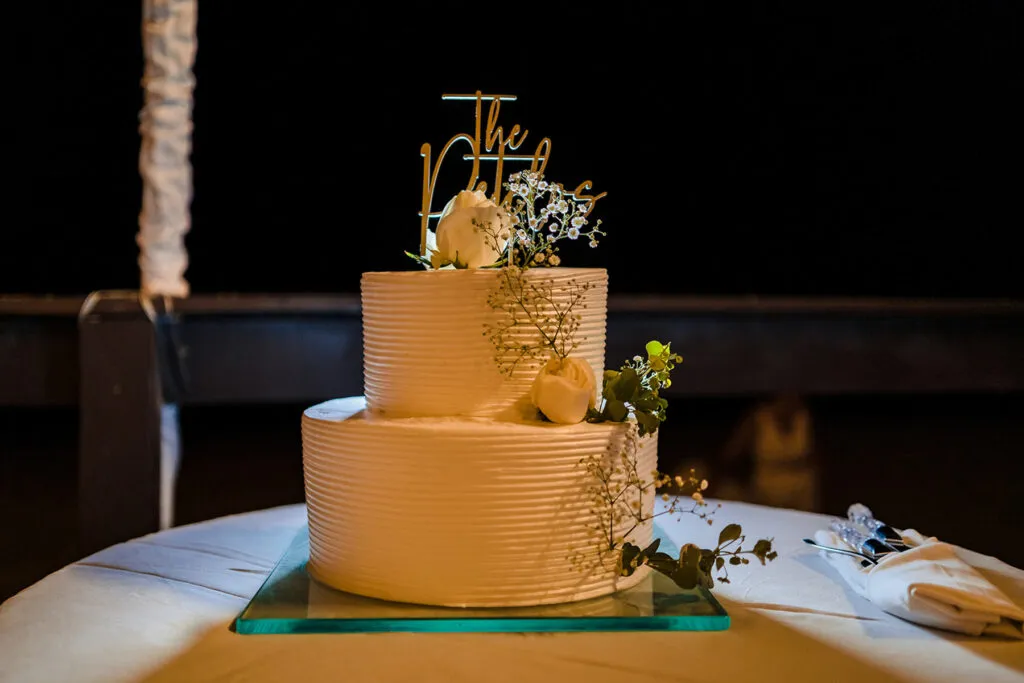 Two-tier wedding cake with white frosting and floral decorations at Cancun Riviera Maya destination wedding celebration