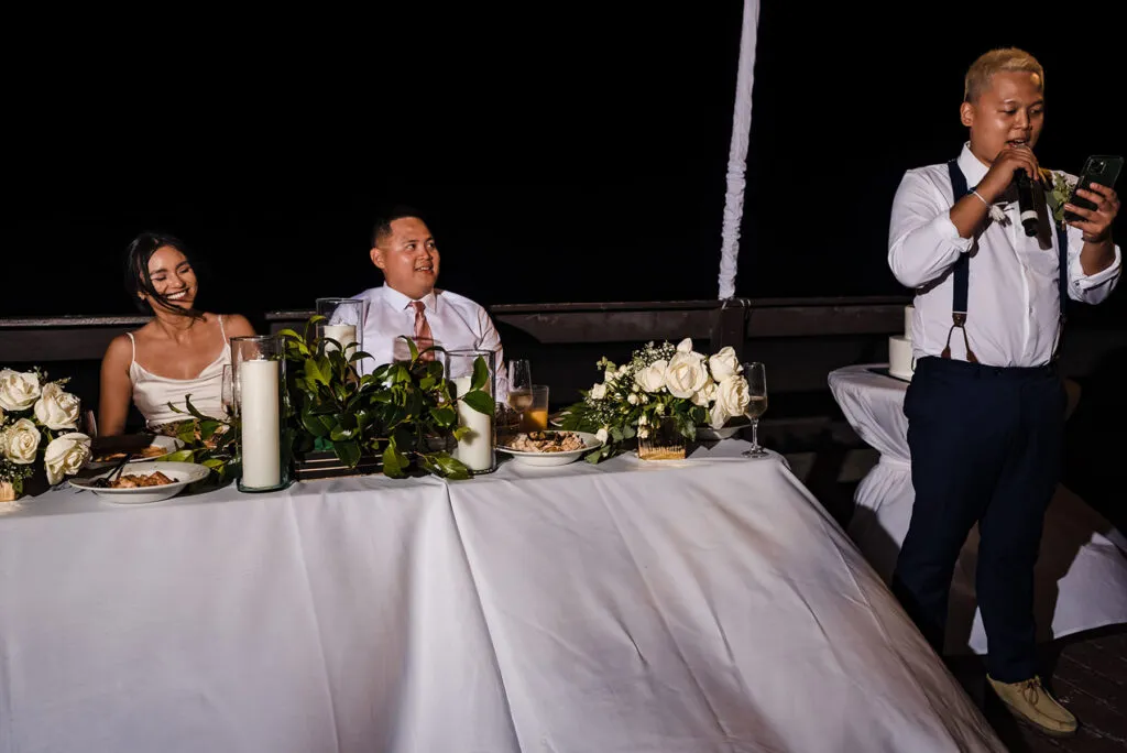 Wedding reception speech at intimate Cancun celebration with bride and groom at head table listening to toast
