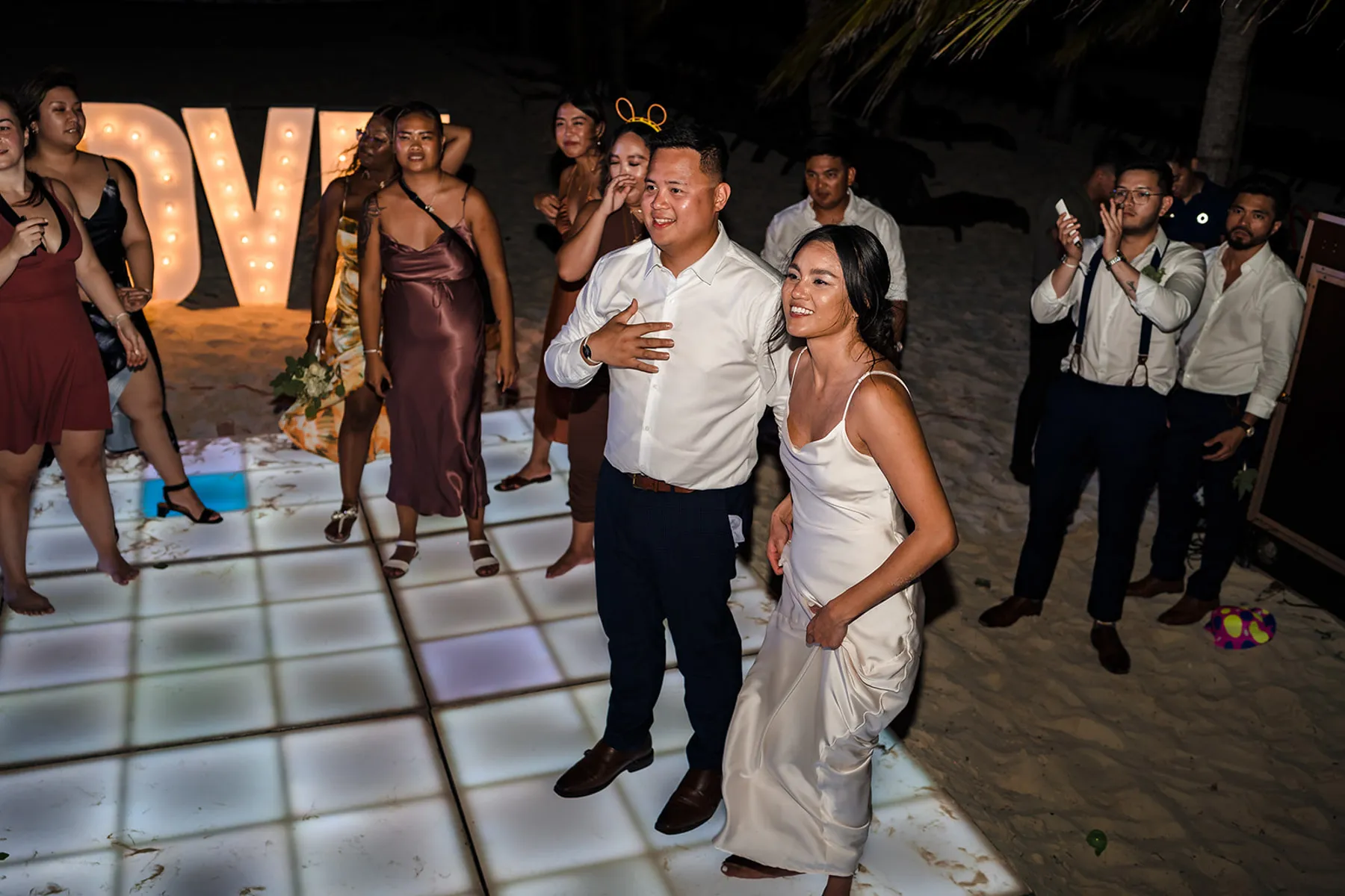 Bride and groom first dance at Cancun beach wedding reception with LED dance floor and tropical palm trees in Mexico