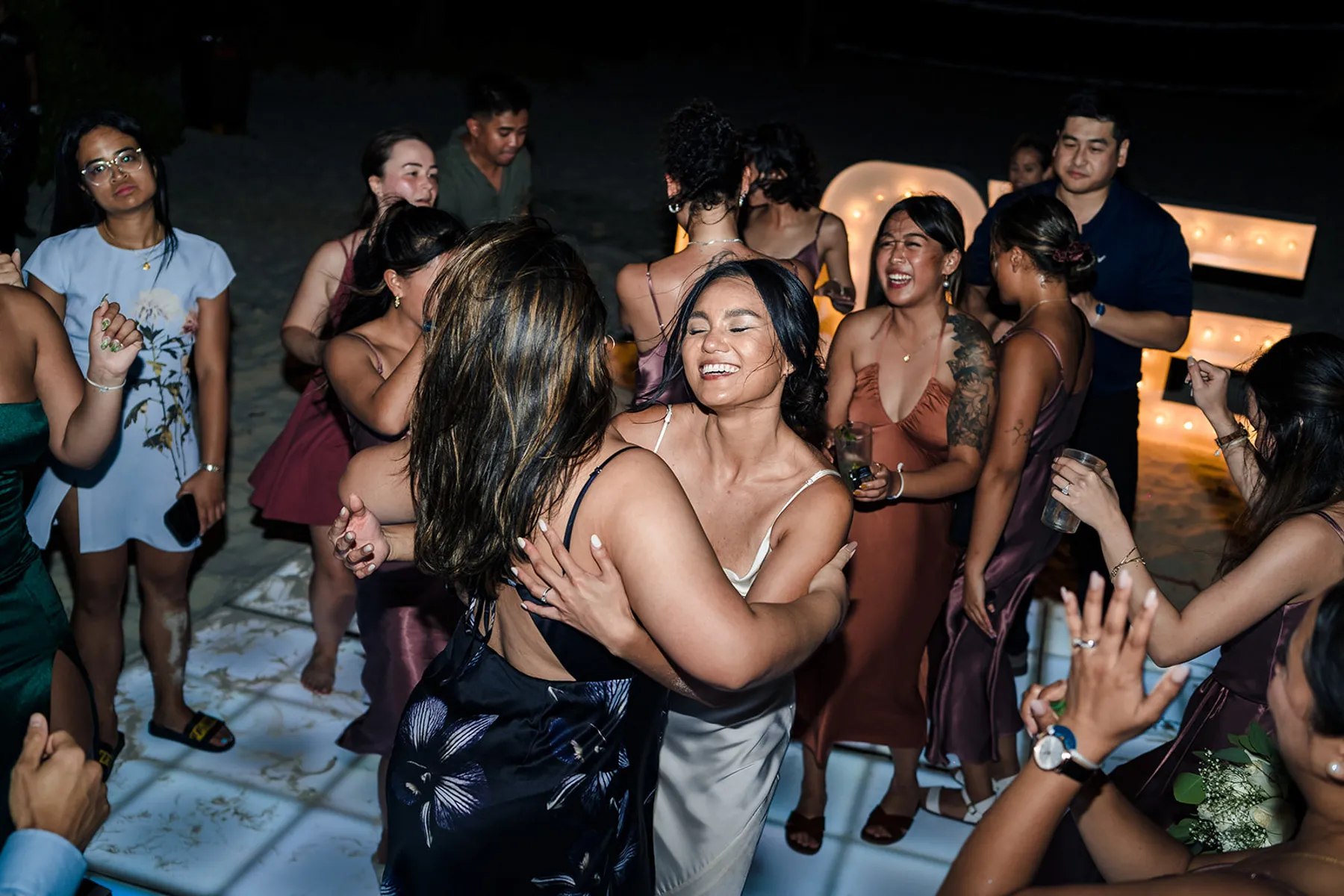 Bride and friends celebrating with joyful embrace at beach wedding reception in Cancun Riviera Maya Mexico destination wedding