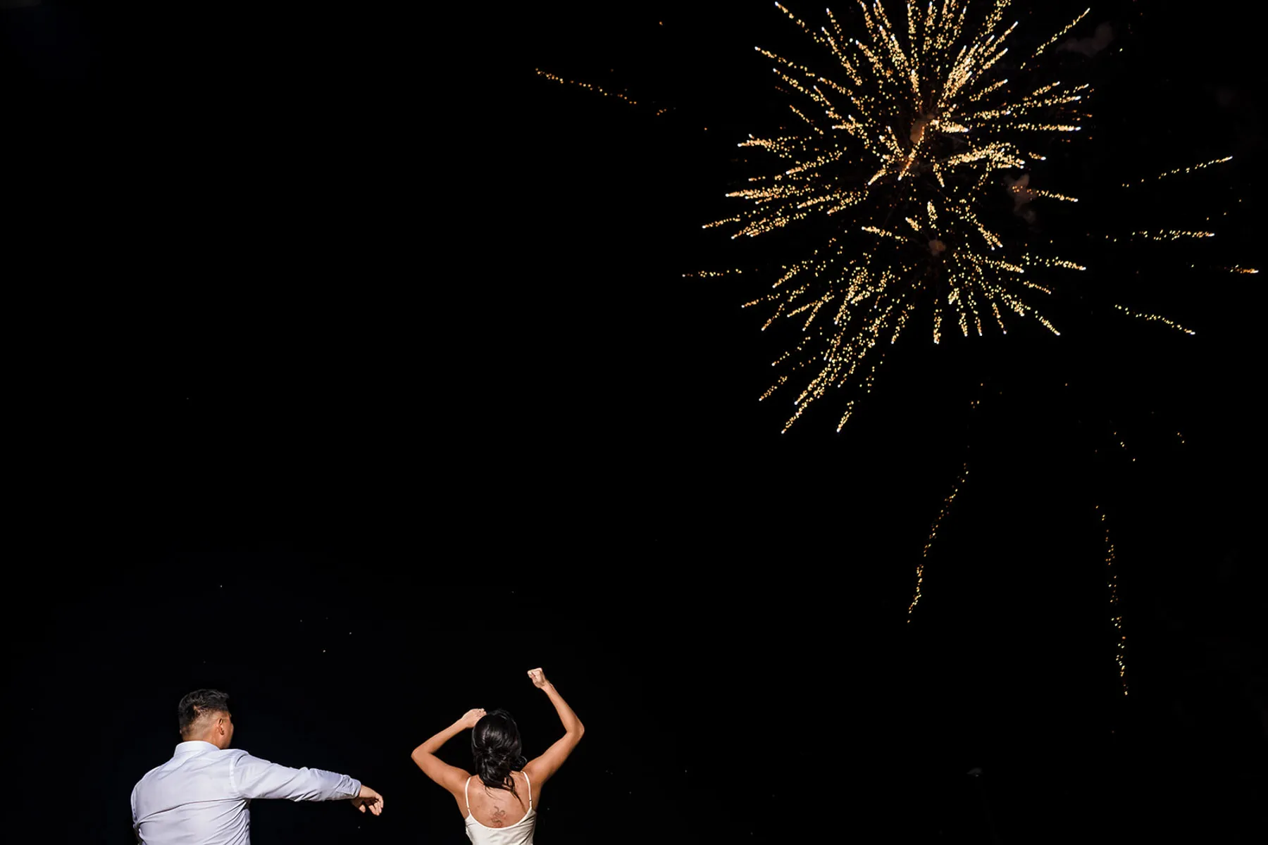 Couple celebrating with golden fireworks display during their wedding reception in Cancun, Mexico - magical moment captured