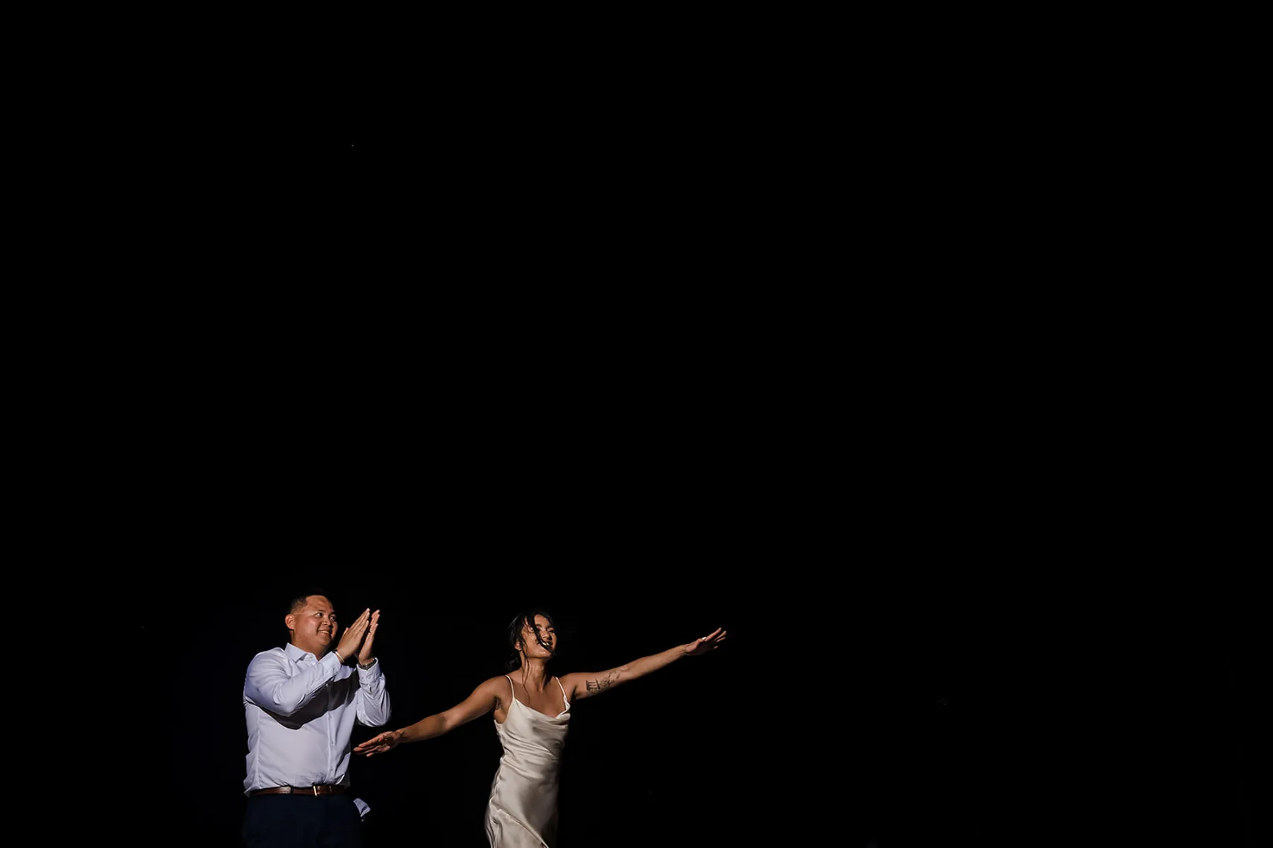 Bride and groom dancing at night during Cancun wedding reception with dramatic lighting in Riviera Maya Mexico