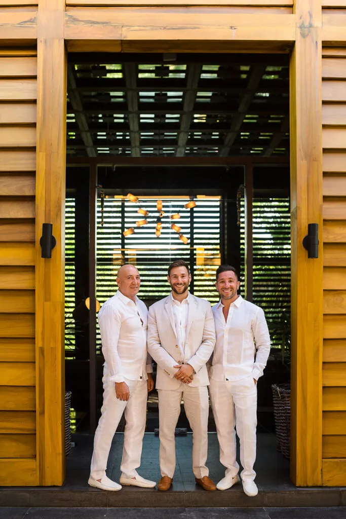 Three men in white linen suits pose for tropical wedding photos at luxury Riviera Maya resort in Cancun Mexico
