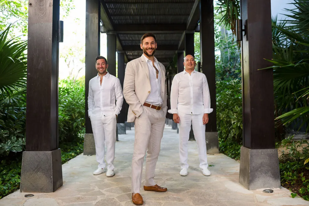 Groom with groomsmen in white linen suits at luxury Riviera Maya resort wedding venue with tropical palm trees