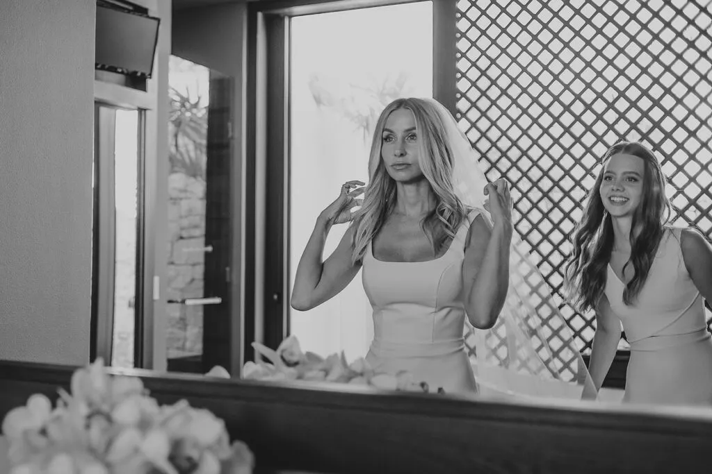 Bride putting on veil with bridesmaid assistance during wedding preparation in Cancun Riviera Maya Mexico destination wedding