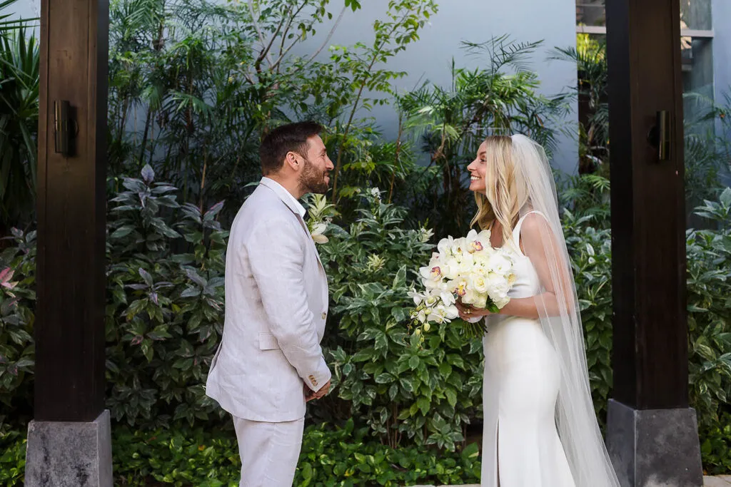 Bride and groom sharing intimate moment in tropical Cancun wedding with white orchid bouquet and lush jungle backdrop