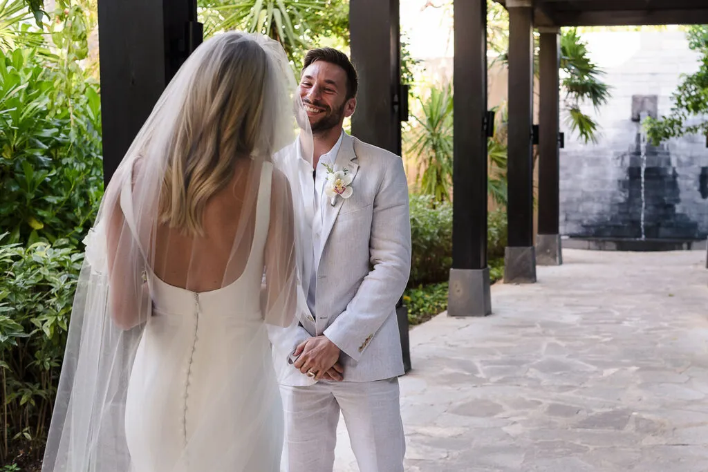 Groom's emotional first look at bride during destination wedding ceremony in Cancun Mexico resort with tropical palms