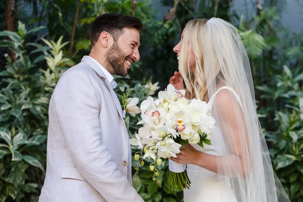 Bride and groom laughing together with white orchid bouquet at tropical Cancun wedding ceremony in Riviera Maya Mexico