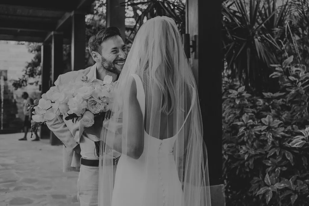 Romantic bride and groom first look moment at Cancun wedding with tropical plants and modern architecture backdrop