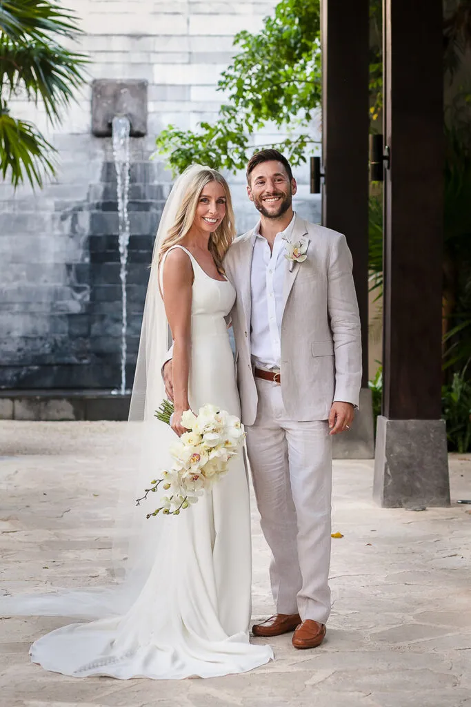 Bride and groom wedding portrait at luxury Riviera Maya resort with tropical fountain backdrop in Cancun Mexico