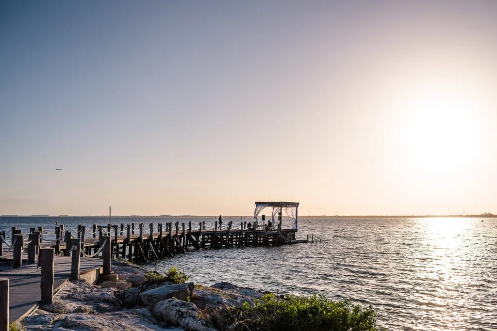 Romantic sunset dock wedding ceremony setup in Riviera Maya Mexico with ocean views and wooden pier for couples photography